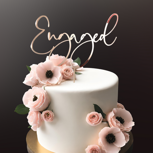 Engaged Cake Topper in rose Gold mirror acyrlic for engagement party on a white cake with pink anemone flowers