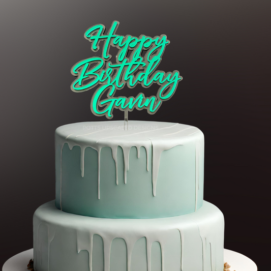 Clear and green mirror happy birthday cake topper personalized with name on a light blue tiered cake
