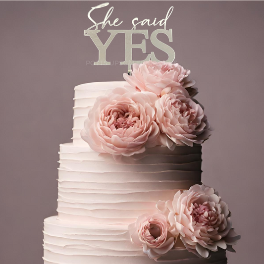 She said yes cake topper in silver mirror on top of a ruffled tier cake with blush pink peony flowers for an engagement cake made by Potts Upscaled Designs LLC