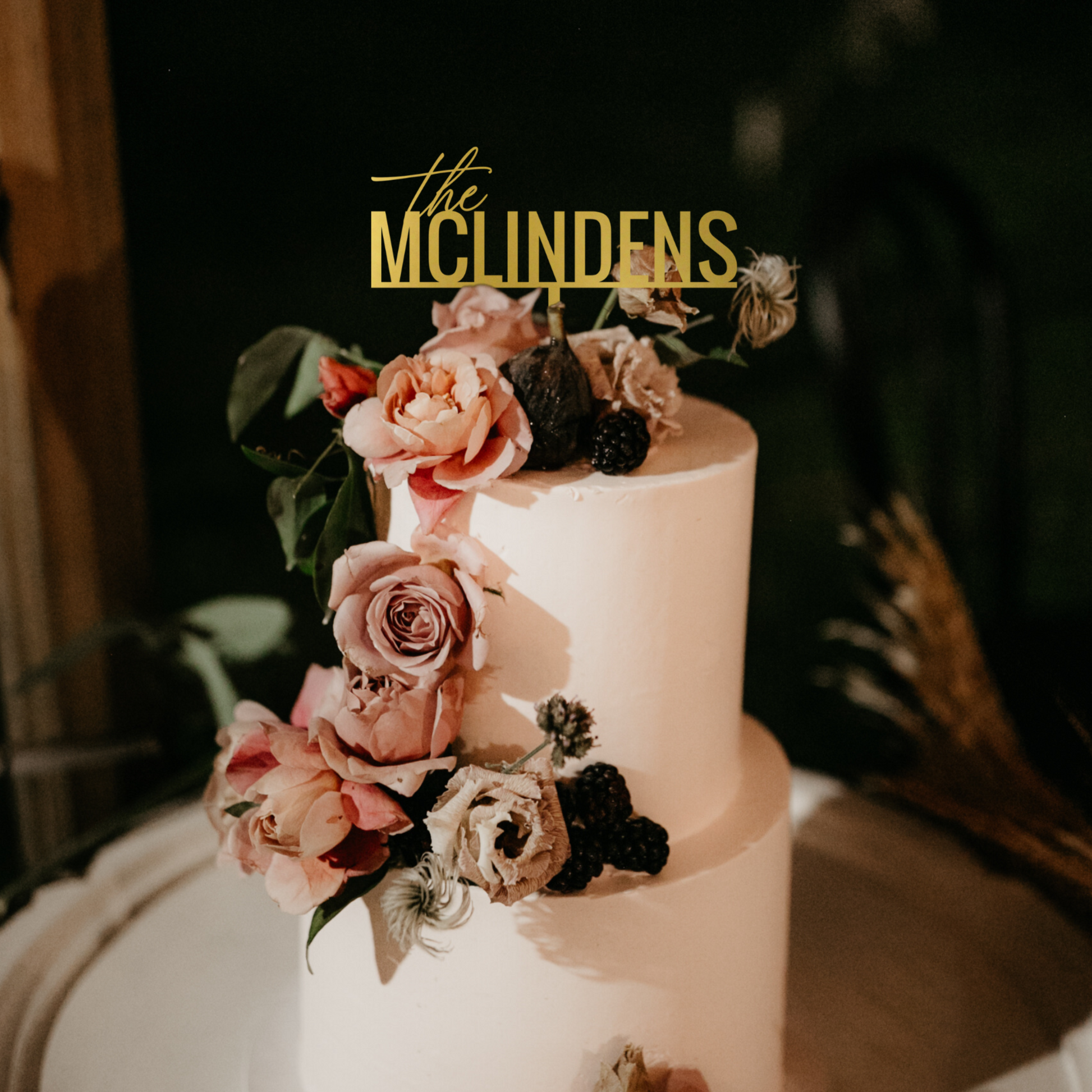 Wedding cake topper personalized with couple's last name in gold mirror on a tiered wedding cake with mauve pink flowers made by Potts Upscaled Designs LLC