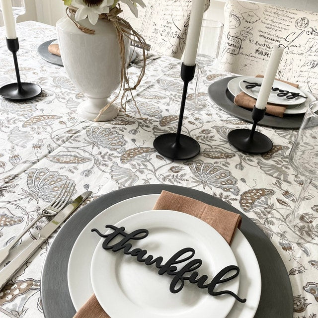 black thankful place card word with flower table cloth in white gold and silver black candle sticks and tan napkins