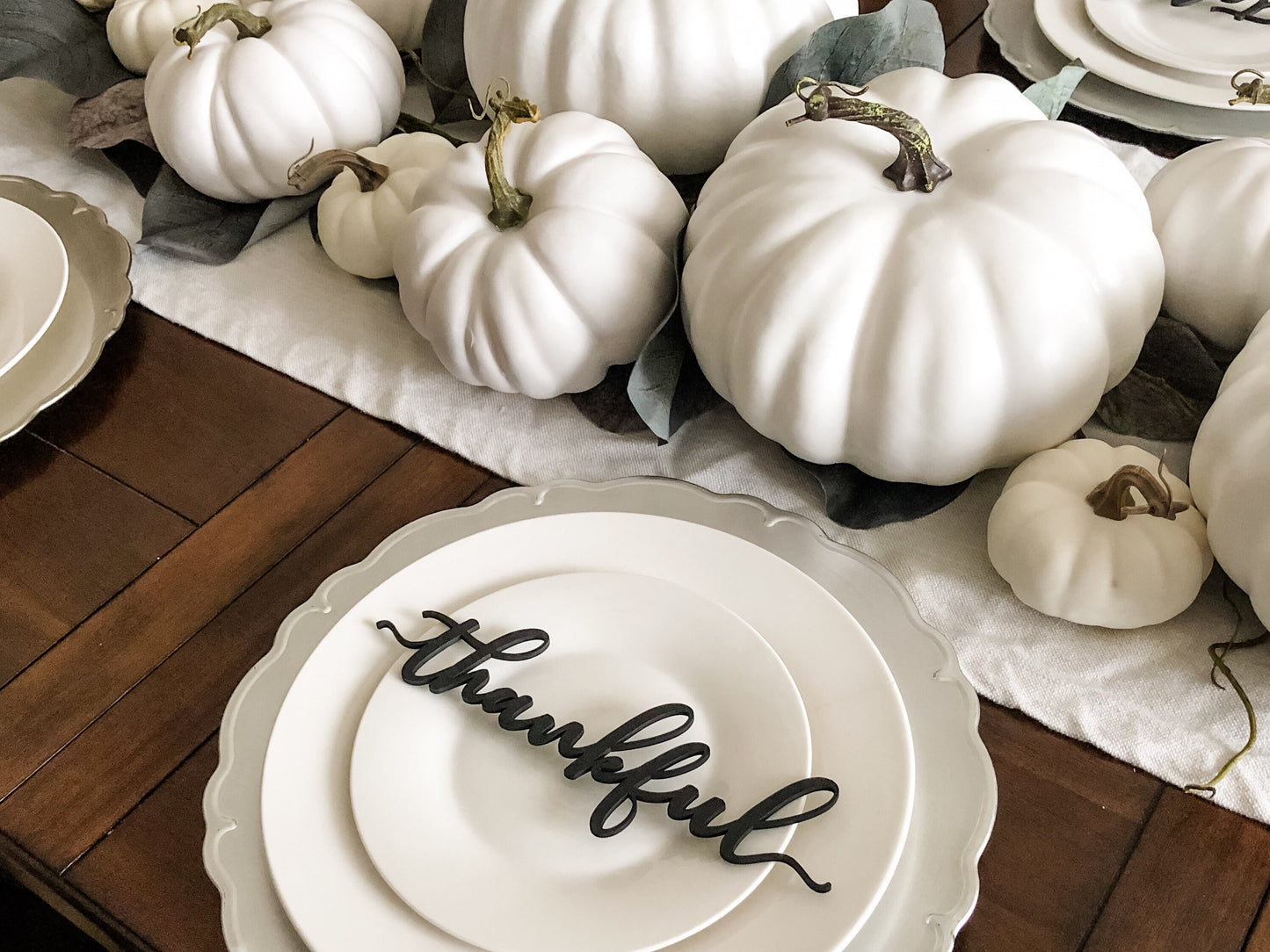 black wood thankful decoration on white plate silver plate charger for thanksgiving dinner decorated with a white pumpkins centerpiece