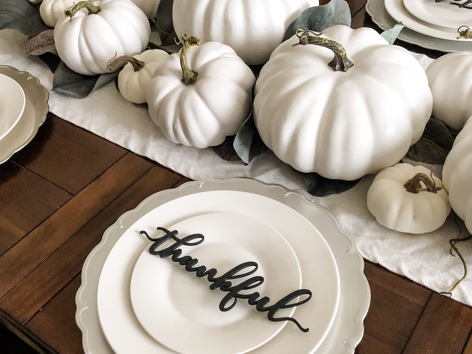 black wood thankful decoration on white plate silver plate charger for thanksgiving dinner decorated with a white pumpkins centerpiece