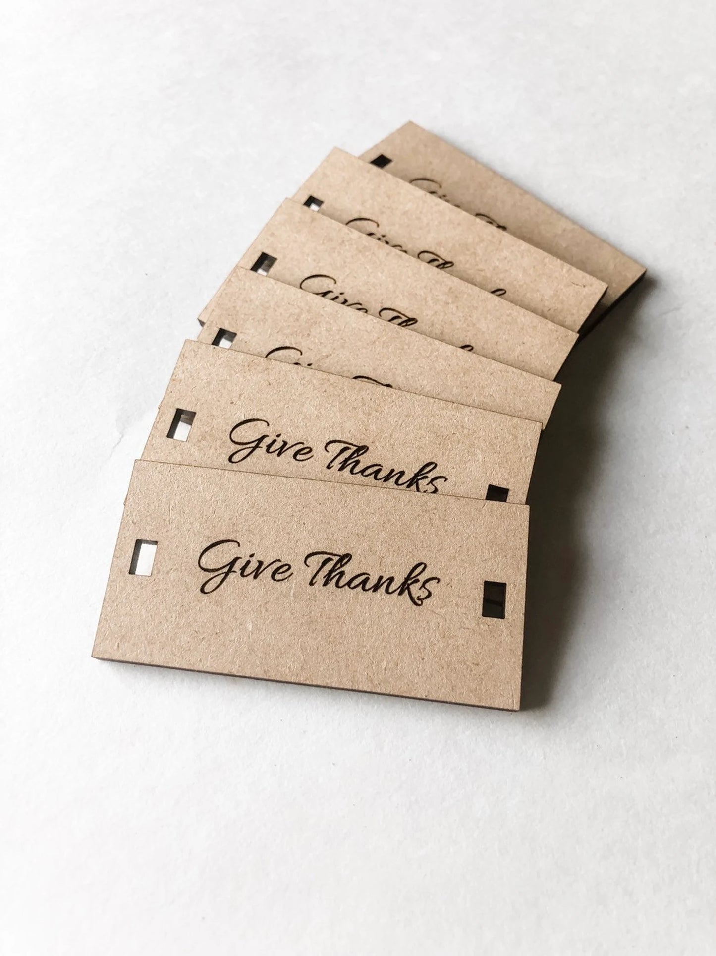 Stack of wood napkin tags with 'Give Thanks' text on a white background