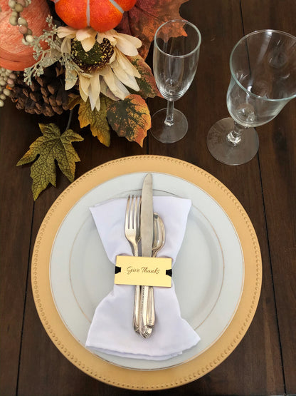 Thanksgiving table setting with gold charger, white plate, silverware, and fall decorations.